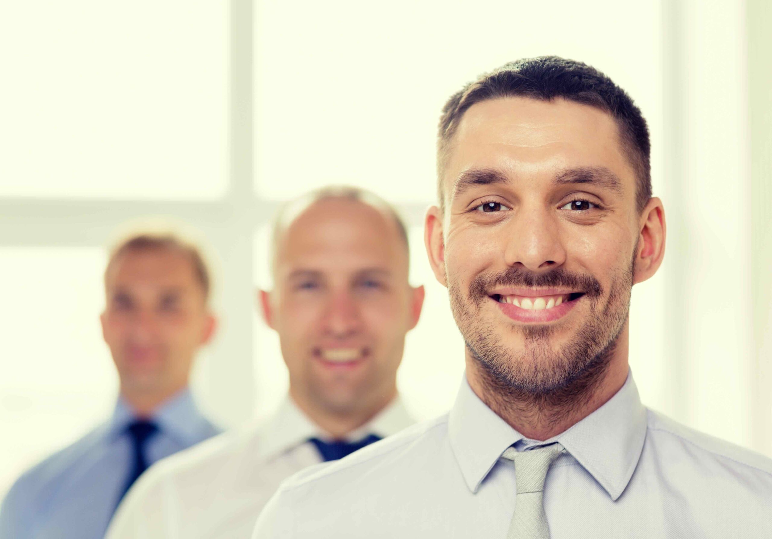 business and office concept - smiling businessman in office with team on the back